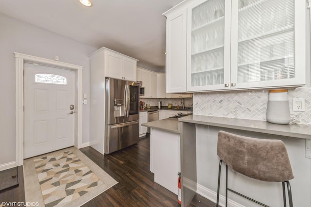 kitchen with stainless steel appliances, a kitchen bar, dark hardwood / wood-style flooring, and white cabinets