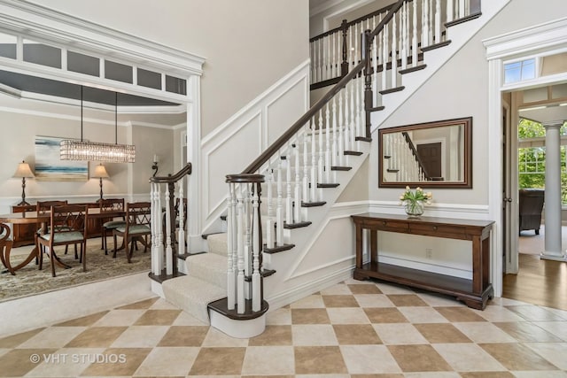 5605 Farmbrook Ln, Crystal Lake, IL 60014 - stairs featuring a decorative wall, a towering ceiling, a chandelier, crown molding, and decorative columns