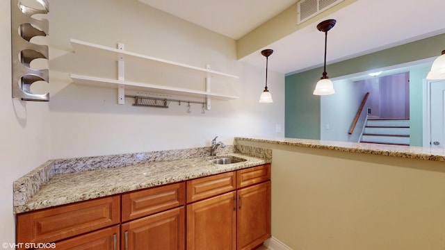 kitchen featuring decorative light fixtures, light stone countertops, and sink