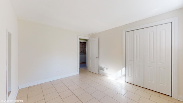 unfurnished bedroom featuring washer / clothes dryer, light tile patterned floors, and a closet