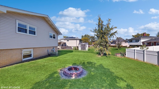 view of yard featuring cooling unit, a storage unit, and an outdoor fire pit