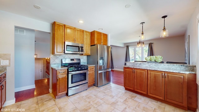 kitchen with stainless steel appliances, light stone countertops, hanging light fixtures, and decorative backsplash