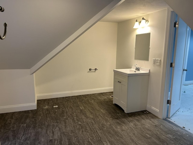 bathroom featuring wood-type flooring, vaulted ceiling, and vanity