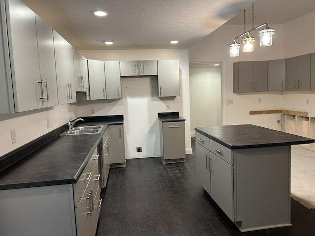 kitchen with sink, decorative light fixtures, dark hardwood / wood-style floors, gray cabinets, and a kitchen island