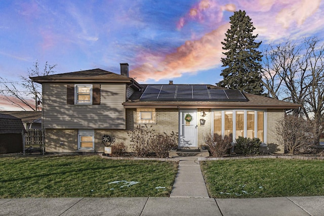 tri-level home featuring a yard and solar panels