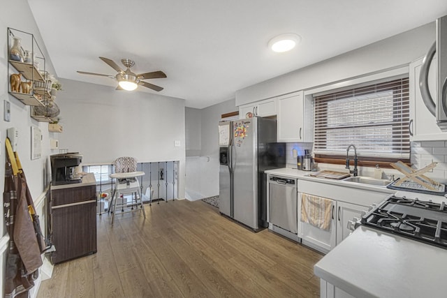 kitchen with appliances with stainless steel finishes, white cabinets, backsplash, hardwood / wood-style flooring, and ceiling fan