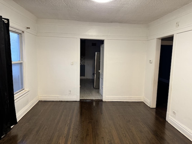 unfurnished room featuring a textured ceiling and dark hardwood / wood-style flooring