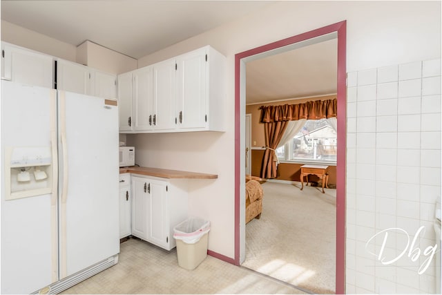 kitchen with white cabinetry, light carpet, and white appliances