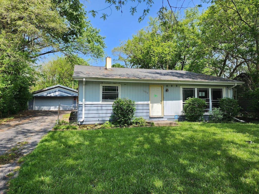 ranch-style house with a garage, an outbuilding, and a front lawn