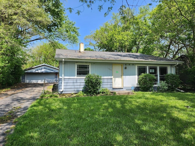 ranch-style house with a garage, an outbuilding, and a front lawn