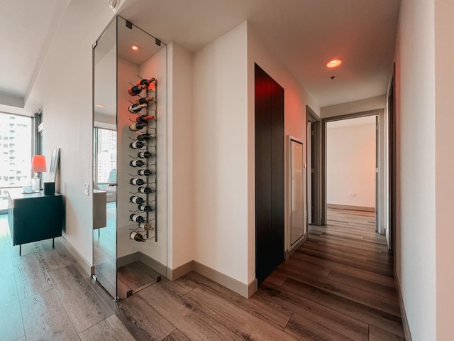 hallway featuring recessed lighting, light wood-style flooring, and baseboards