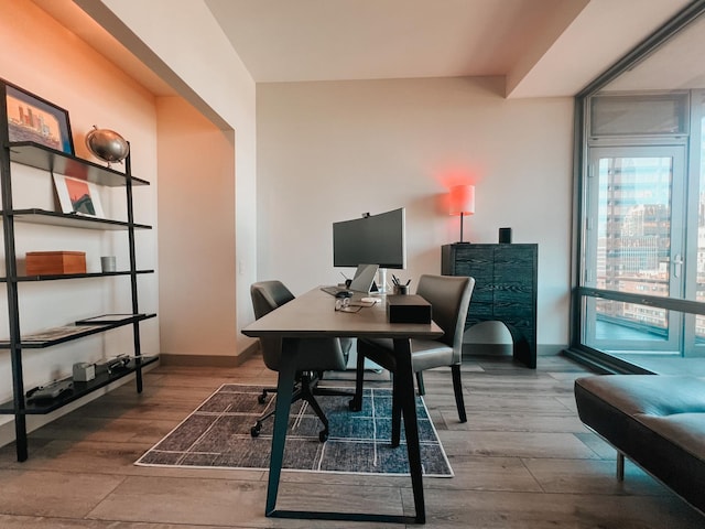 home office with a wall of windows, baseboards, and wood finished floors