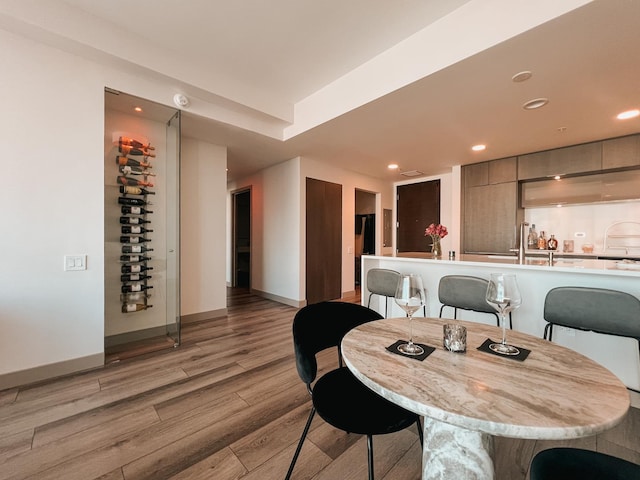 dining area with baseboards, light wood-type flooring, and recessed lighting