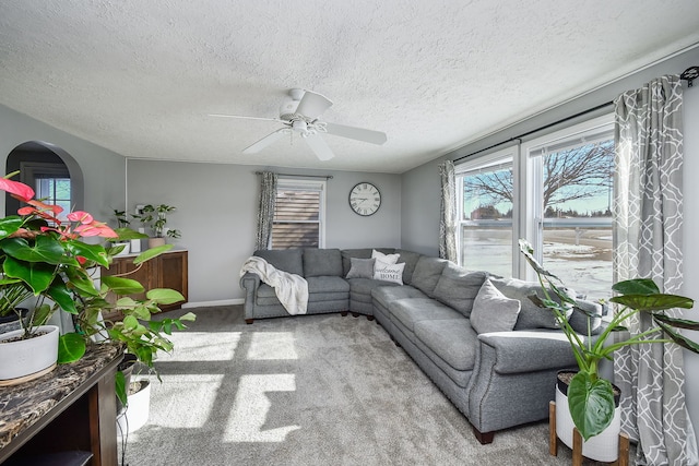 carpeted living room with a textured ceiling and ceiling fan