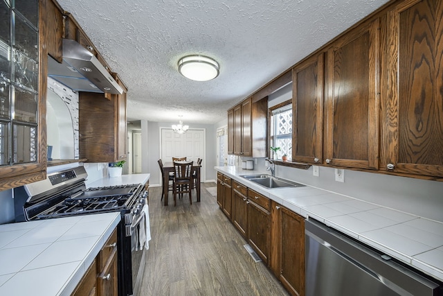 kitchen with sink, stainless steel appliances, a notable chandelier, tile counters, and dark hardwood / wood-style flooring