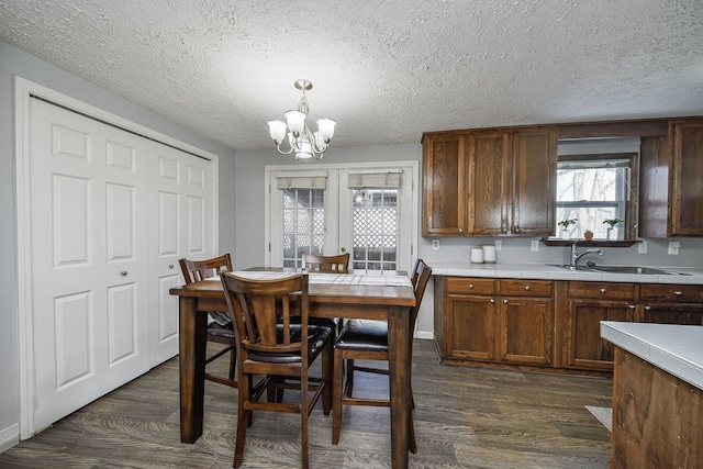 dining space featuring sink, a textured ceiling, a notable chandelier, and dark hardwood / wood-style flooring