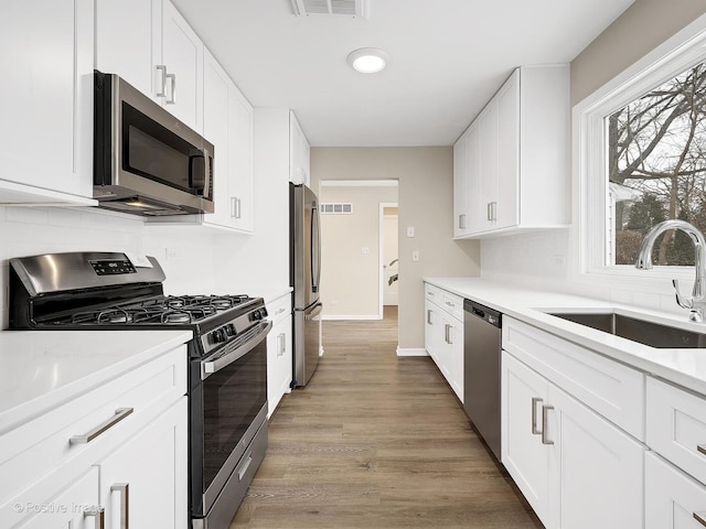 kitchen with white cabinetry, stainless steel appliances, light hardwood / wood-style floors, and sink