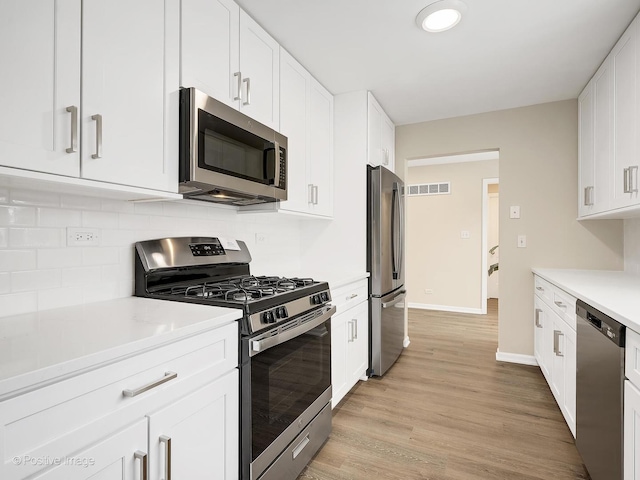 kitchen with decorative backsplash, stainless steel appliances, light hardwood / wood-style flooring, and white cabinets