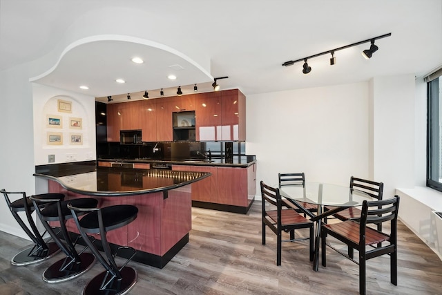 kitchen featuring a kitchen bar, sink, tasteful backsplash, kitchen peninsula, and light hardwood / wood-style floors