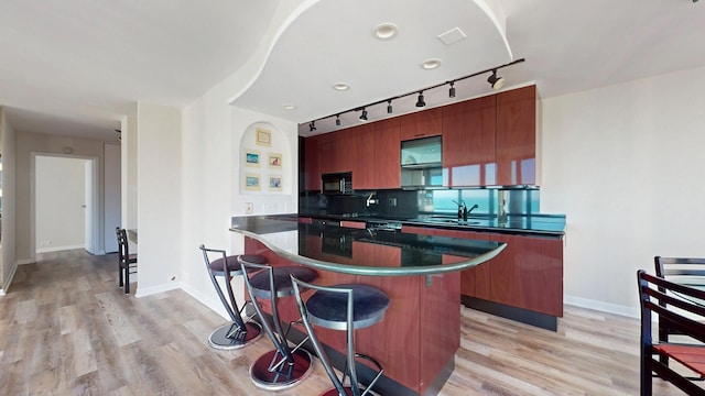 kitchen featuring a kitchen island, sink, a breakfast bar area, and light wood-type flooring