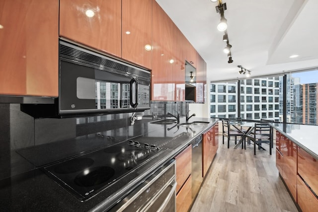 kitchen featuring black appliances, sink, decorative backsplash, and light wood-type flooring