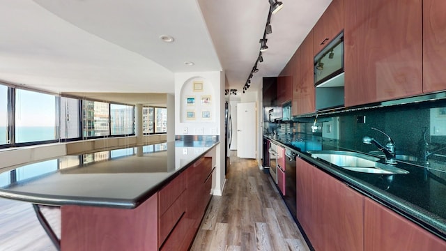 kitchen featuring tasteful backsplash, sink, black dishwasher, a water view, and light hardwood / wood-style flooring