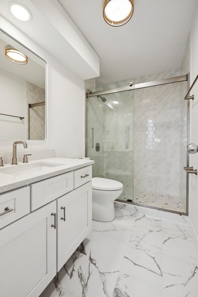 bathroom featuring a shower with door, vanity, and toilet