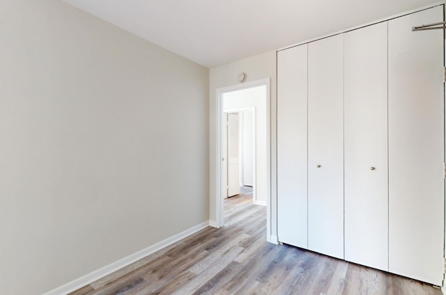 unfurnished bedroom with light hardwood / wood-style flooring and a closet