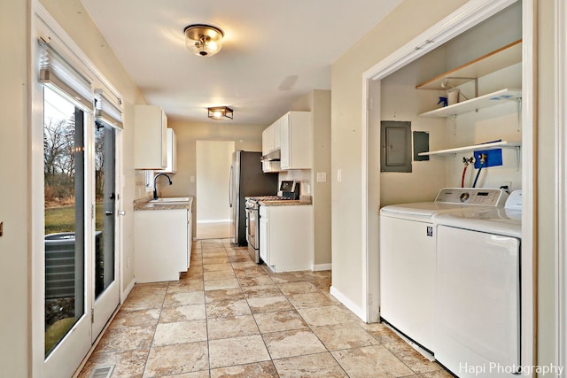 interior space featuring sink, gas stove, white cabinetry, electric panel, and independent washer and dryer