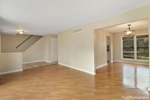 unfurnished room featuring light wood-type flooring and a notable chandelier