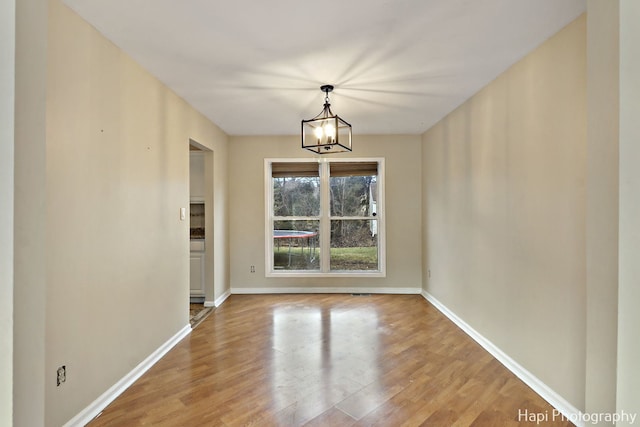 unfurnished dining area featuring hardwood / wood-style floors and a notable chandelier