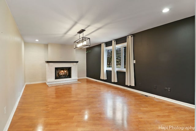 unfurnished living room featuring a brick fireplace and light wood-type flooring