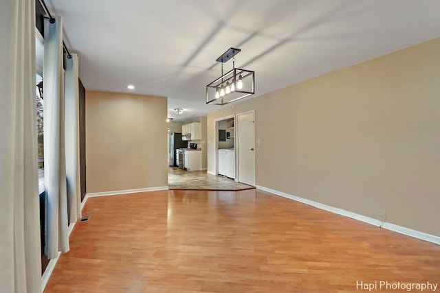 unfurnished dining area with washing machine and clothes dryer and light hardwood / wood-style flooring