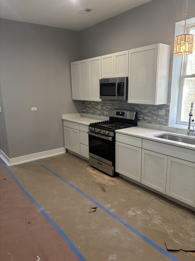 kitchen with sink, white cabinets, pendant lighting, stainless steel appliances, and backsplash