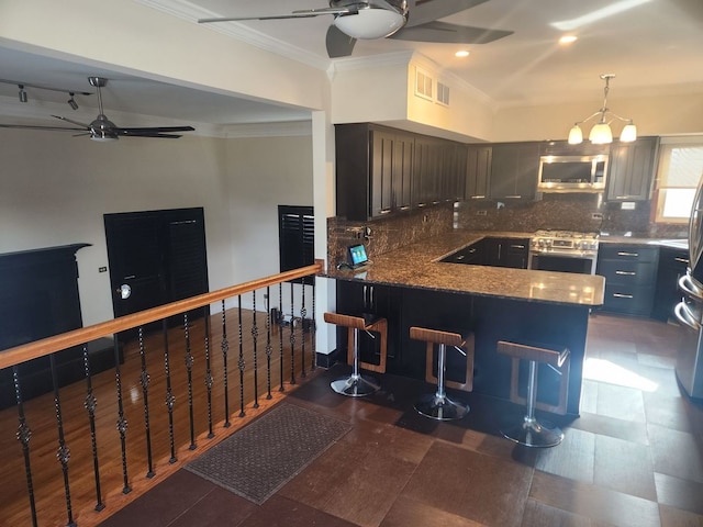 kitchen featuring ornamental molding, kitchen peninsula, ceiling fan, stainless steel appliances, and decorative backsplash