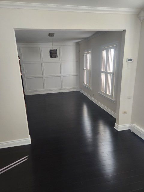 empty room with ornamental molding and dark hardwood / wood-style floors