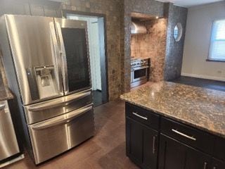 kitchen with stainless steel fridge with ice dispenser and light stone countertops