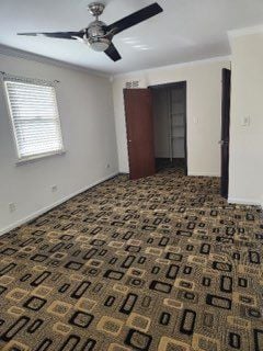 spare room featuring crown molding, dark carpet, and ceiling fan