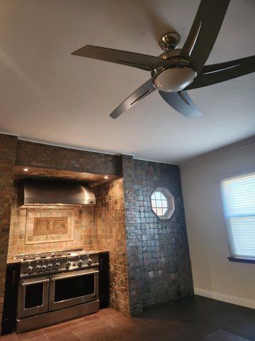 kitchen featuring double oven range, wall chimney exhaust hood, and ceiling fan