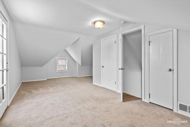 bonus room with light carpet and vaulted ceiling