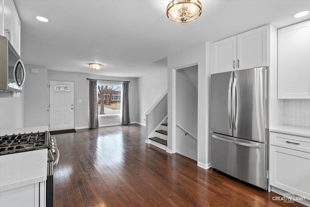 kitchen featuring white cabinetry, stainless steel appliances, dark wood-type flooring, and decorative backsplash