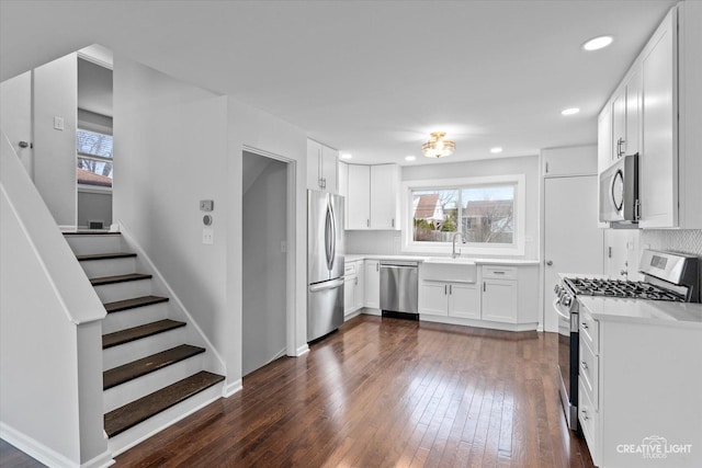 kitchen with appliances with stainless steel finishes, white cabinetry, sink, dark hardwood / wood-style flooring, and a healthy amount of sunlight