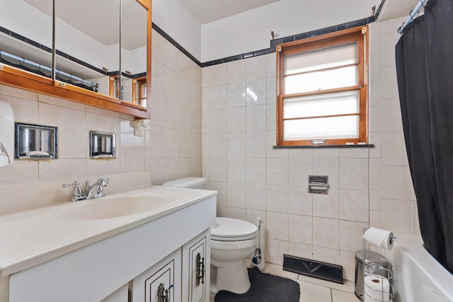 bathroom with vanity, toilet, tile patterned flooring, and tile walls