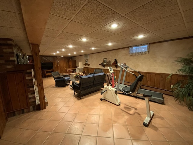 exercise area with light tile patterned flooring, a paneled ceiling, and wooden walls