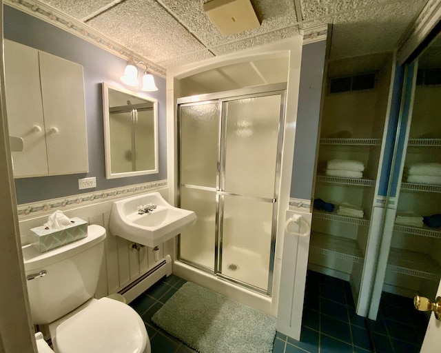 bathroom with sink, a paneled ceiling, a baseboard heating unit, a shower with shower door, and tile patterned floors