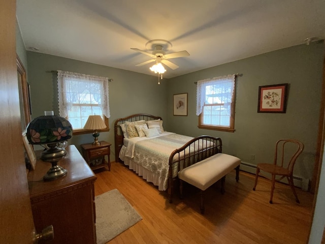 bedroom with baseboard heating, ceiling fan, and light wood-type flooring