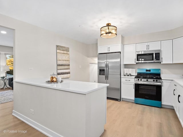 kitchen featuring appliances with stainless steel finishes, kitchen peninsula, light wood-type flooring, and white cabinets