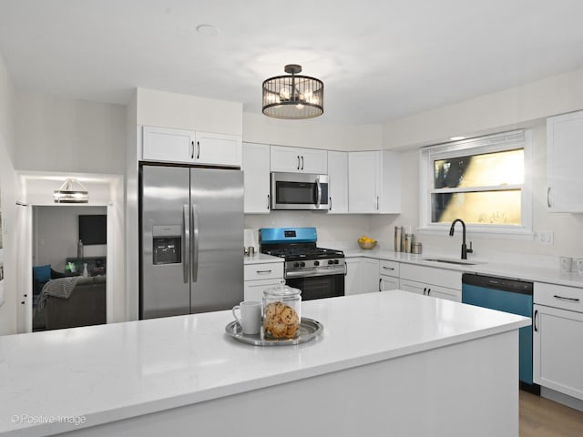 kitchen with sink, appliances with stainless steel finishes, a notable chandelier, light hardwood / wood-style floors, and white cabinets