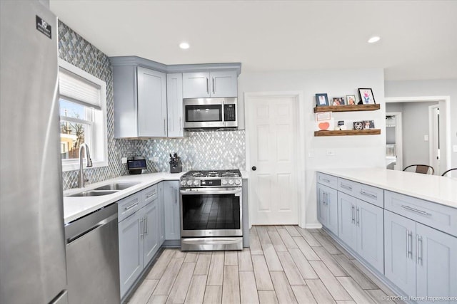 kitchen with gray cabinetry, sink, light hardwood / wood-style floors, and appliances with stainless steel finishes