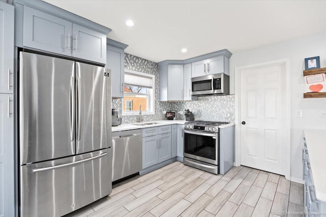 kitchen featuring tasteful backsplash, sink, stainless steel appliances, and gray cabinetry